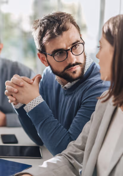Business professional in glasses and blue sweater engaged in focused conversation in meeting room